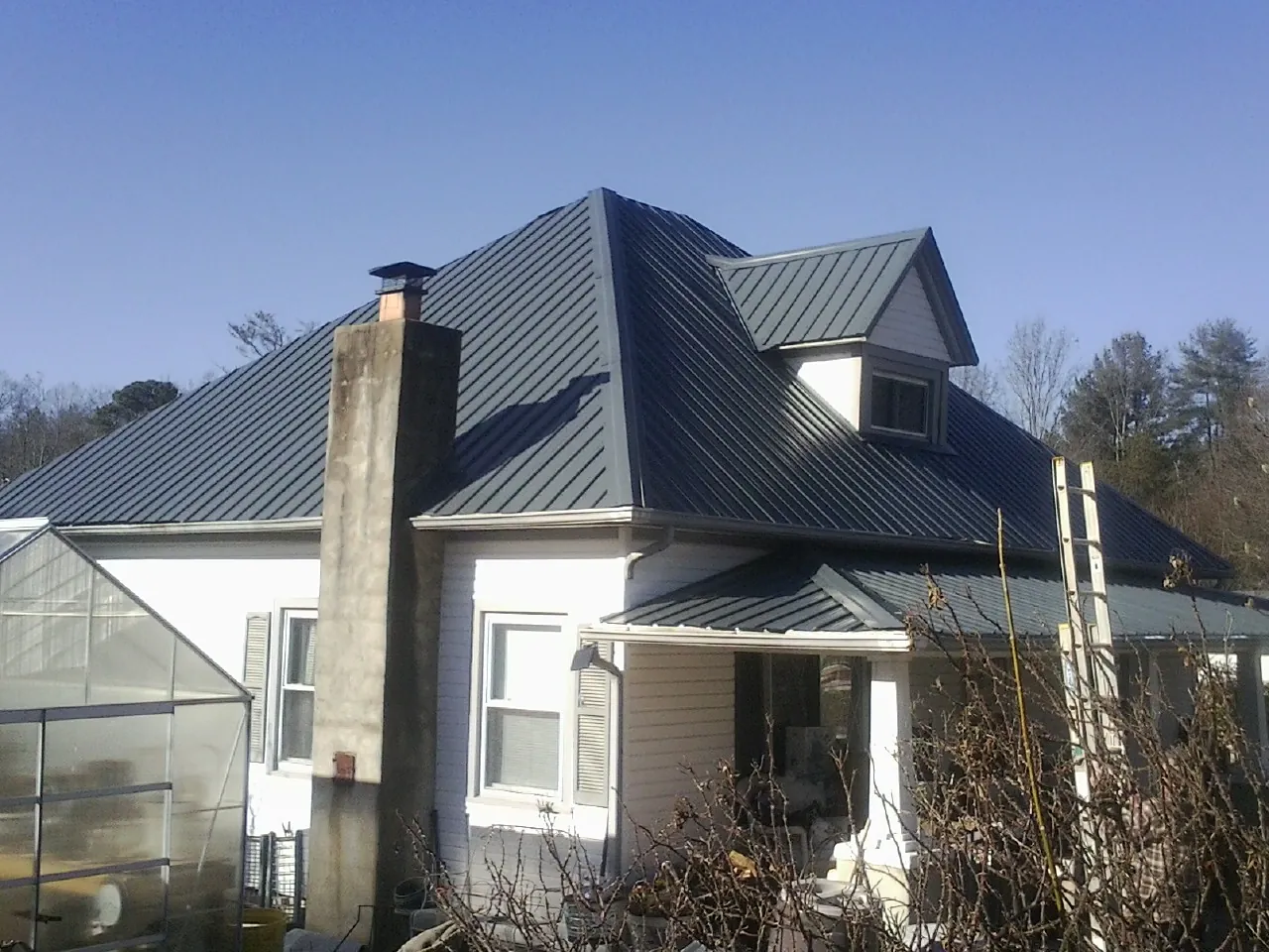 Dark blue standing seam metal roof on a white farmhouse with dormer — Slate & Tile Roof Repair by Roofing Brothers in Herculaneum