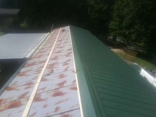 Old rusted panels beside newly installed green metal roofing — Wind Damage Roof Repair by Roofing Brothers in Herculaneum