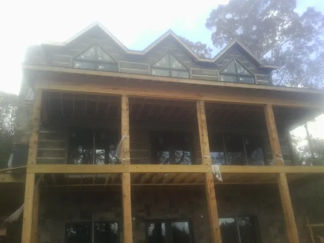 Dormers and porch framing on a large log home under construction — Roof Coating work by our crew in Herculaneum