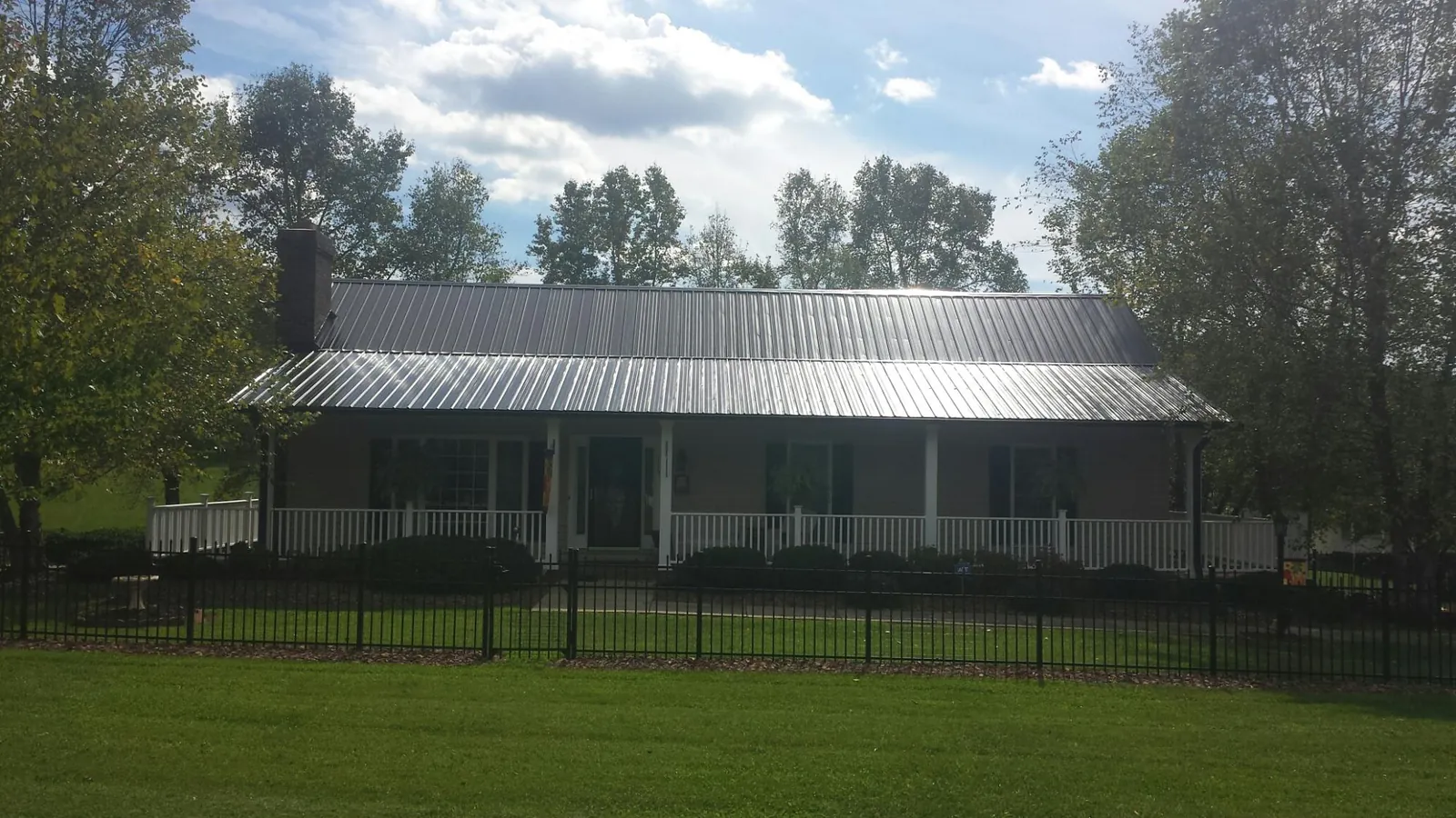 Gray metal roof on a brick ranch with a full width front porch — Gutter Guard Installation work by our crew in Herculaneum