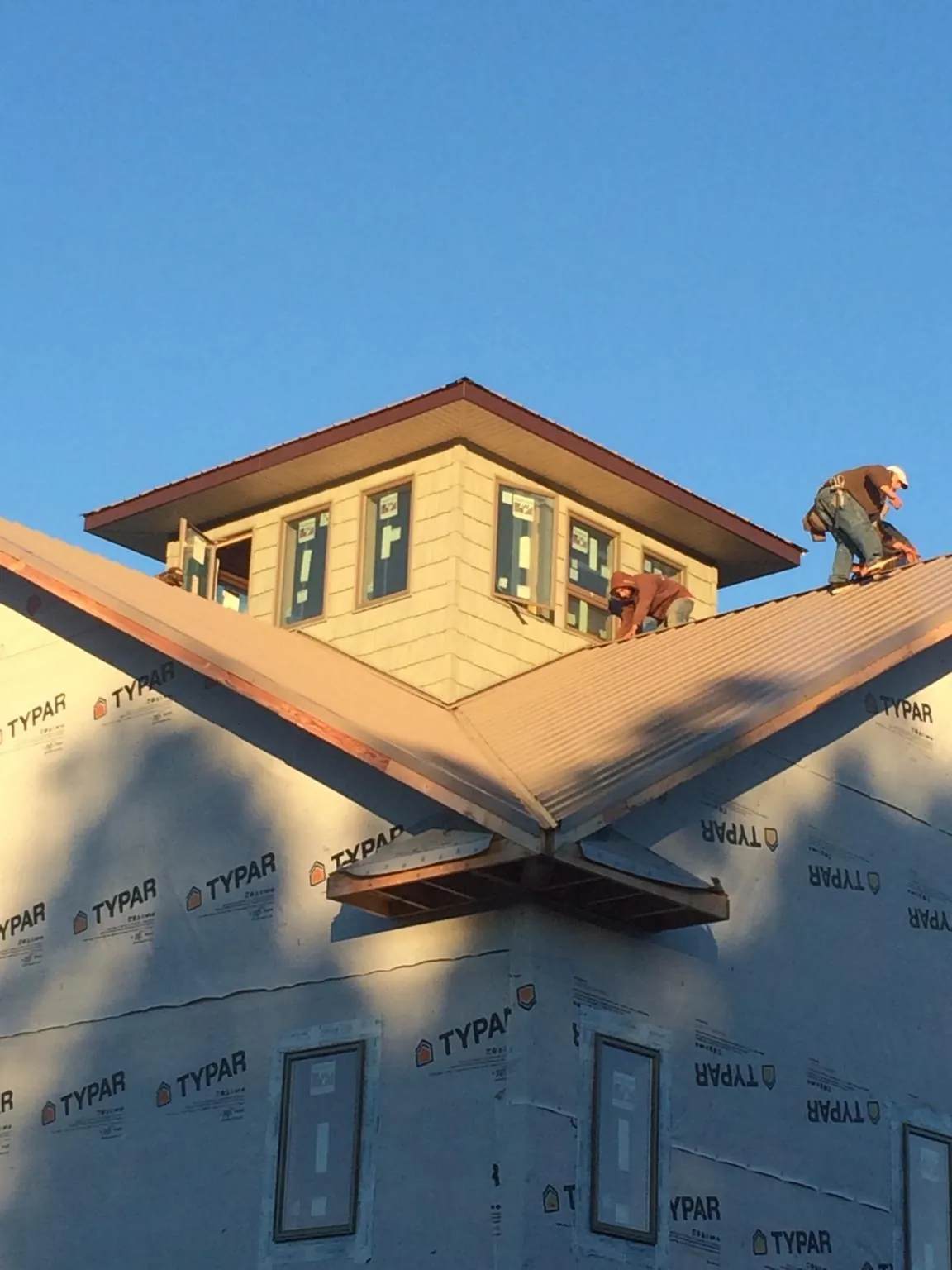 Roofers working around a rooftop cupola on a new metal roof at sunset — Roof Waterproofing in Herculaneum by Roofing Brothers